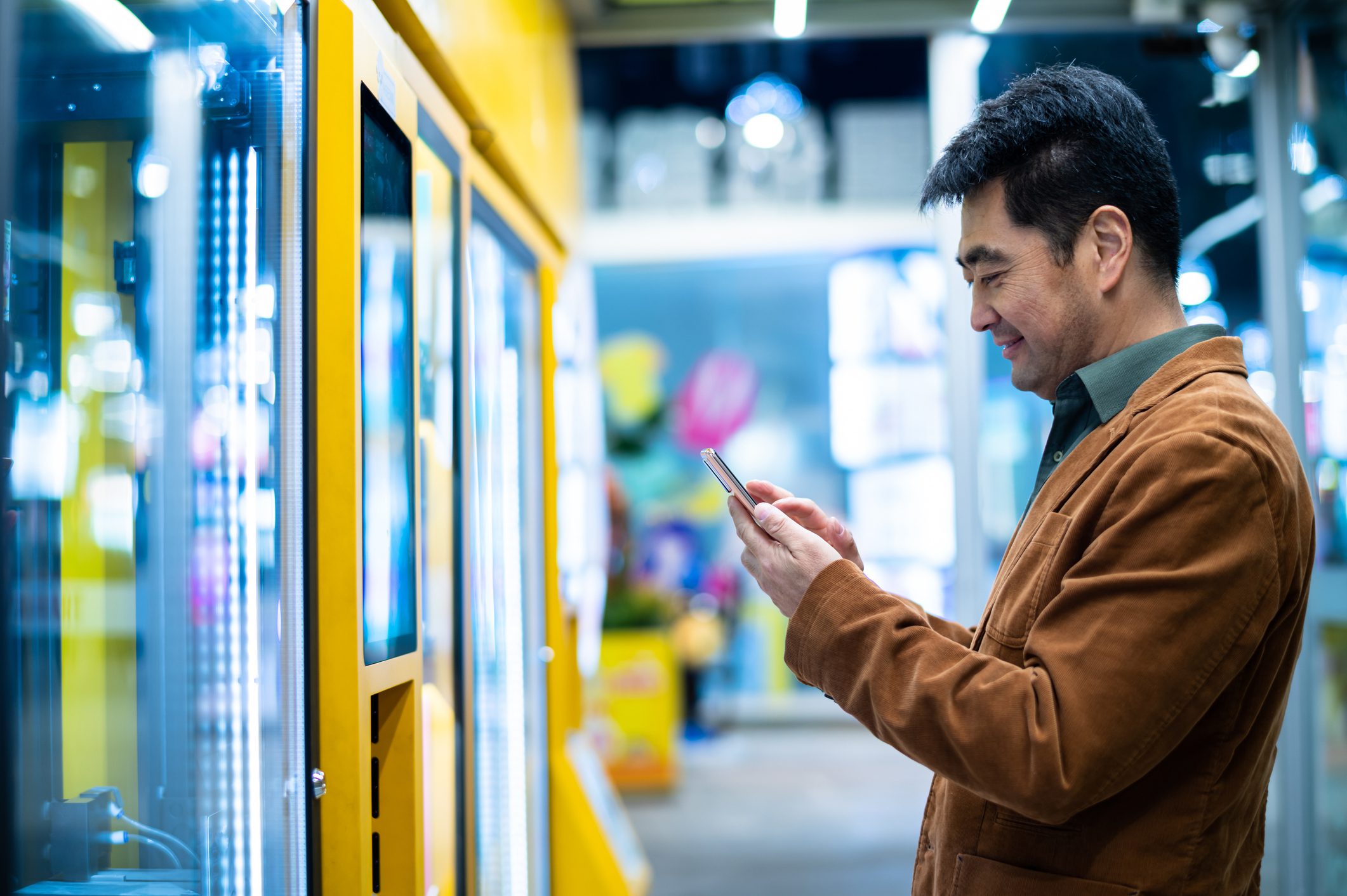 Man using phone beside arcade claw machines