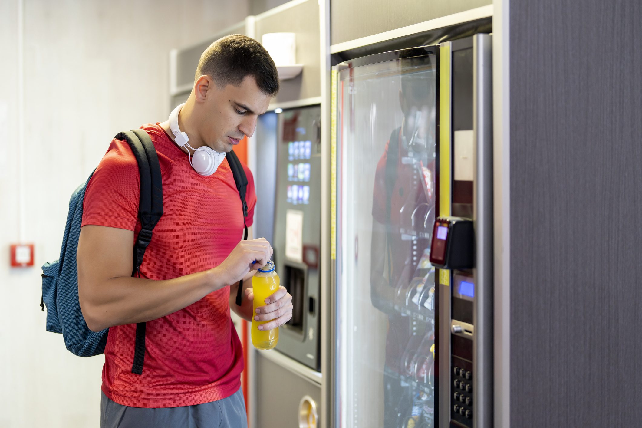 Young man opening bottled drink at vending machine